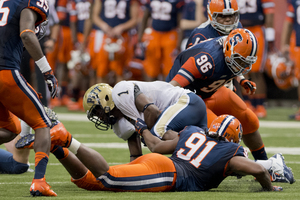 Syracuse defensive linemen Brandon Sharpe and Jay Bromley bring down Pittsburgh running back Ray Graham in the Orange's 14-13 win on Friday. Syracuse's defense held Pittsburgh to only 27 total rushing yards and sacked Panthers quarterback Tino Sunseri five times. 