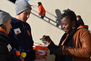 As part of a student-organized disaster relief fundraiser, Andrew Perodeau, left, accepts a donation from a fan attending the Syracuse football game on Saturday. 