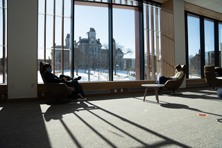 Students relax and work by the natural light of the large windows on the top floor of Schine.