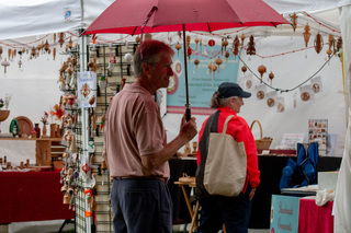 Adorned by a red umbrella to protect him from the rain, an older man checks out a handmade ornament booth. Hung throughout the tent, the ornaments remained shielded from the weather and ready to be taken home by buyers. 